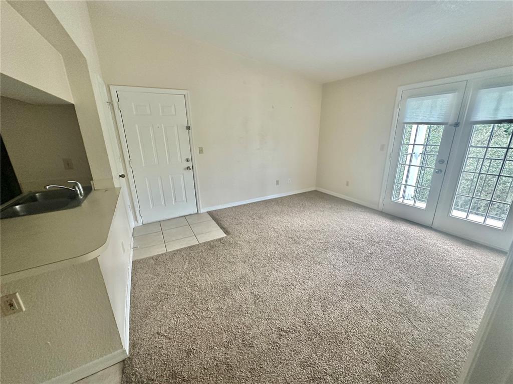 A carpeted living area features a white entry door, French doors, and a kitchen counter — 2550 N ALAFAYA TRAIL UNIT 10305, ORLANDO, FL
