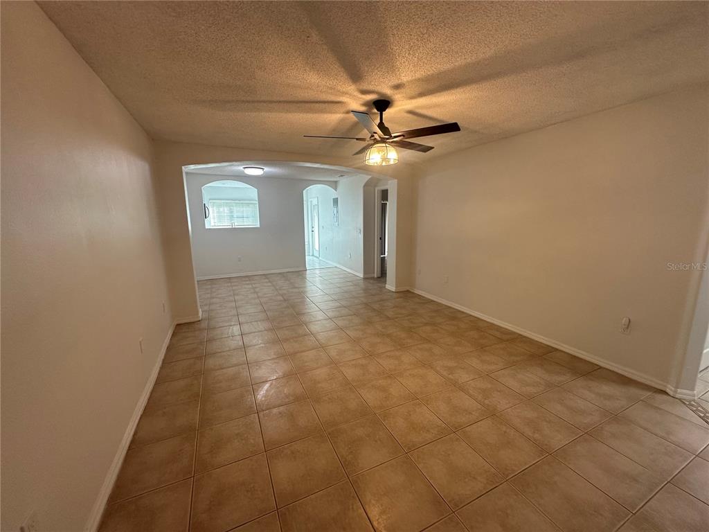 An empty room with beige tile flooring, a ceiling fan, and an arched entryway — 2838 OSPREY COVE PLACE UNIT 103, KISSIMMEE, FL