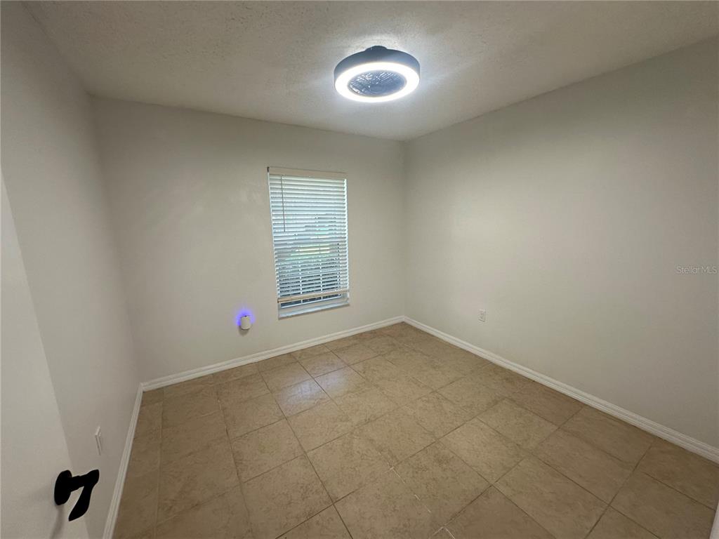An empty room features light-colored walls, tile flooring, a window with blinds, and a ceiling light — 2838 OSPREY COVE PLACE UNIT 103, KISSIMMEE, FL