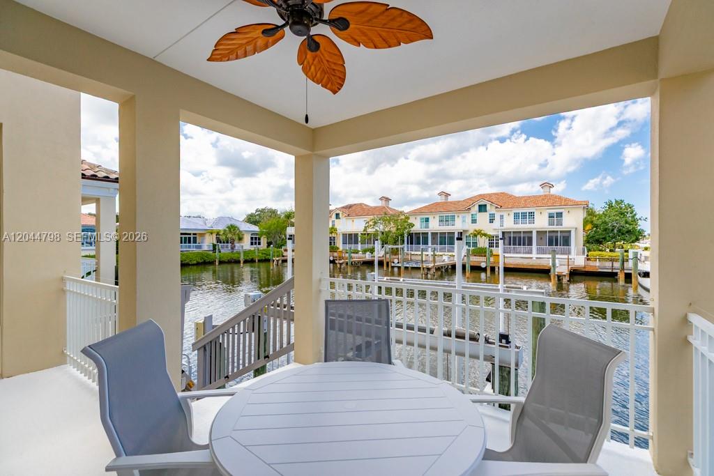 A covered balcony features a dining set, a ceiling fan, and a view of a canal — VERO BEACH, FL