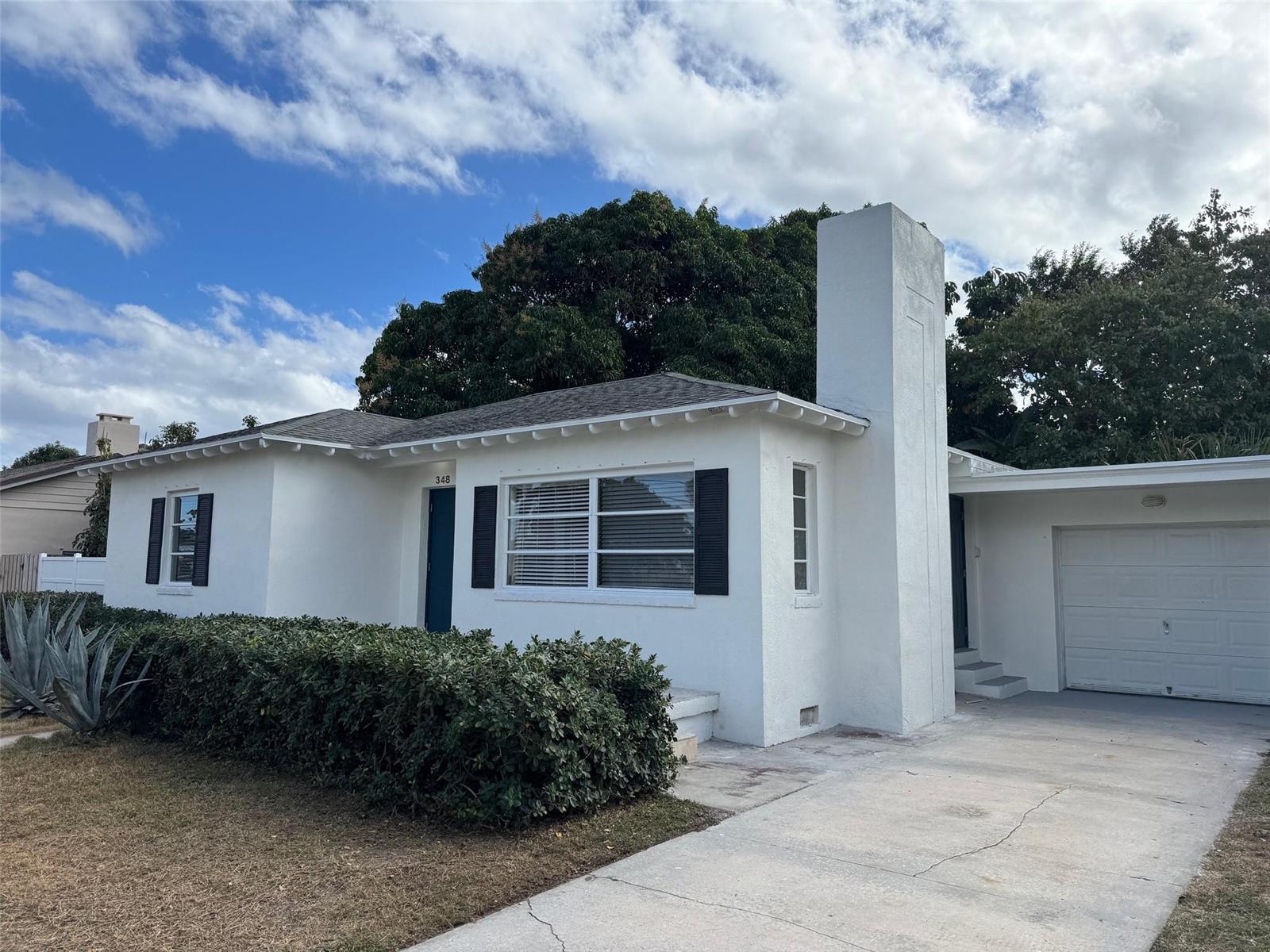 A white, single-story house with a chimney, black shutters, and an attached garage — 348 Gregory Road, West Palm Beach FL 33405, WEST PALM BEACH, FL