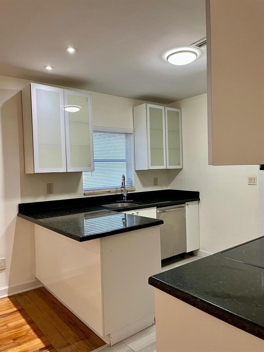 A kitchen features white cabinets, black countertops, a stainless steel dishwasher, and a window — 348 Gregory Road, West Palm Beach FL 33405, WEST PALM BEACH, FL