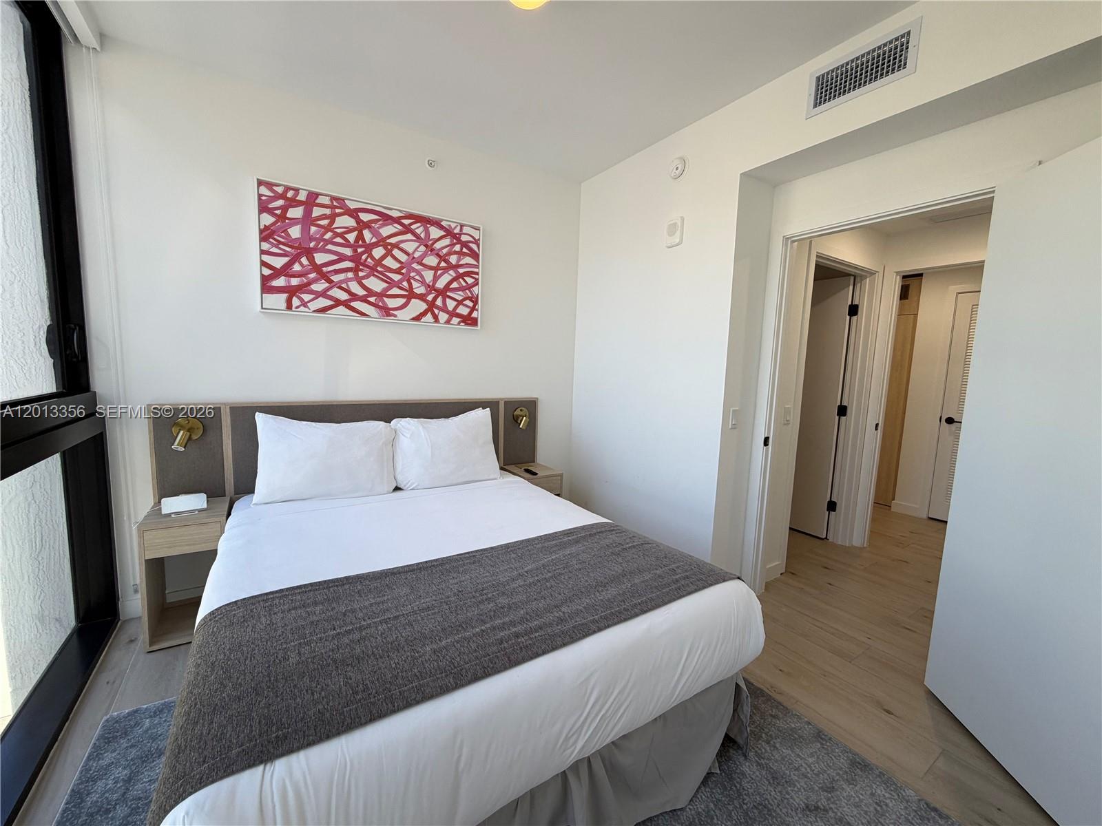 A bedroom features a queen bed, a gray runner, wall art, and light wood flooring — 225 N Miami Ave # 1412, Miami FL 33128, MIAMI, FL