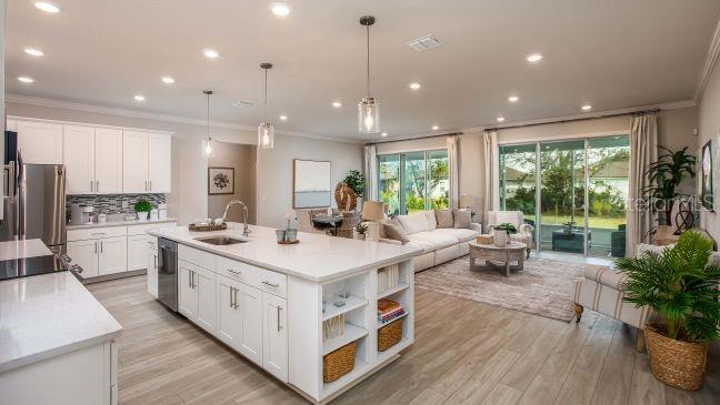 An open-concept kitchen with a large white island flows into a living room with sliders — TBD KNOTTY PINE AVENUE, NORTH PORT, FL