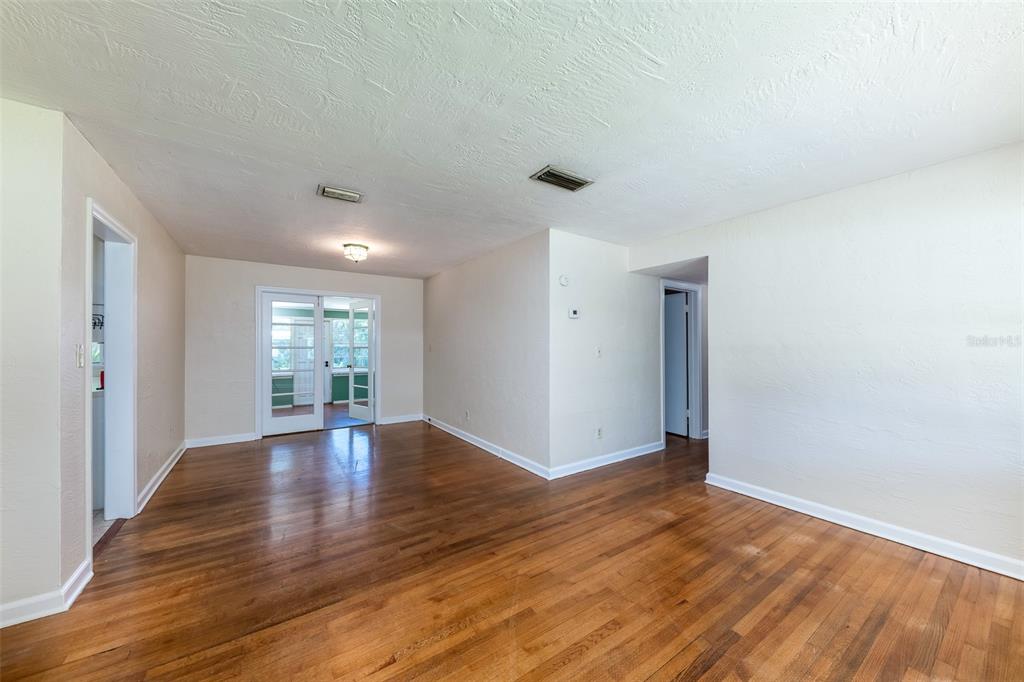 An empty room with hardwood floors, white walls, and French doors leading to a sunroom — 519 VERN DRIVE, ORLANDO, FL