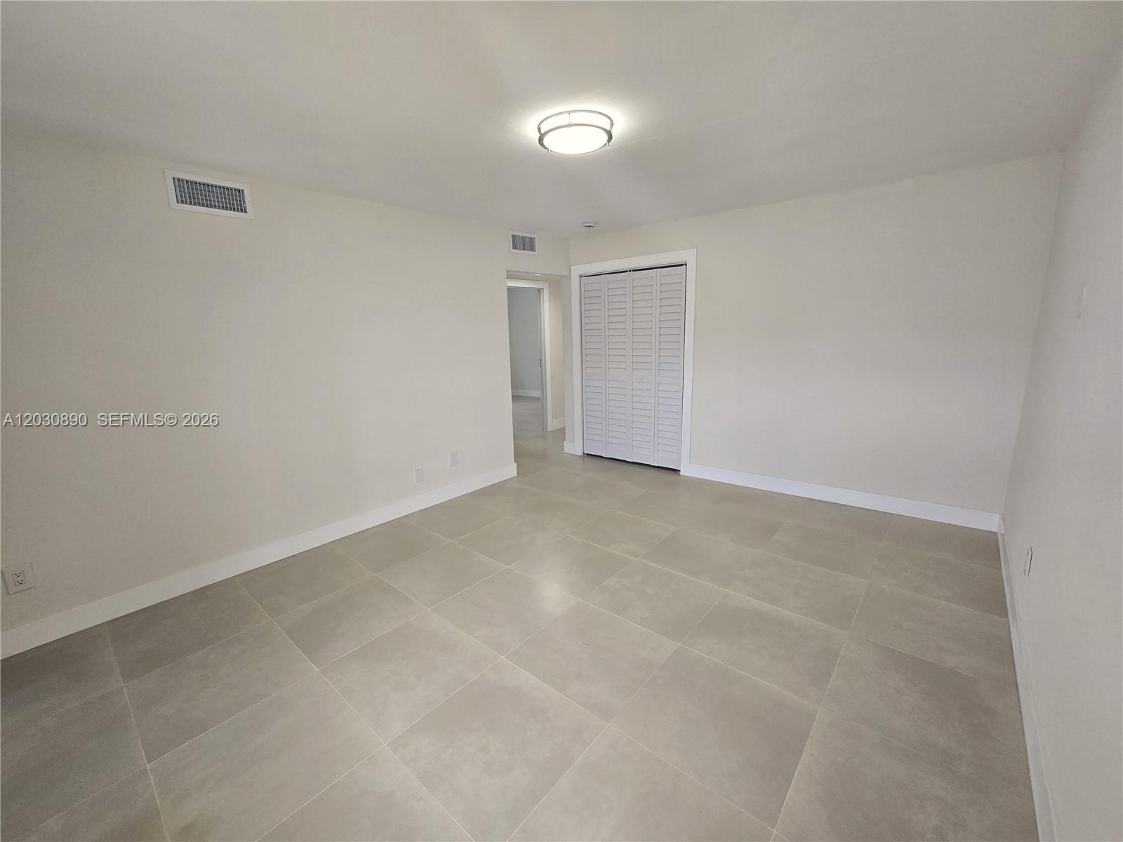 An empty room features light-colored walls, large gray floor tiles, and a white closet — 8891 SW 36th St # 8891, Miami FL 33165, MIAMI, FL