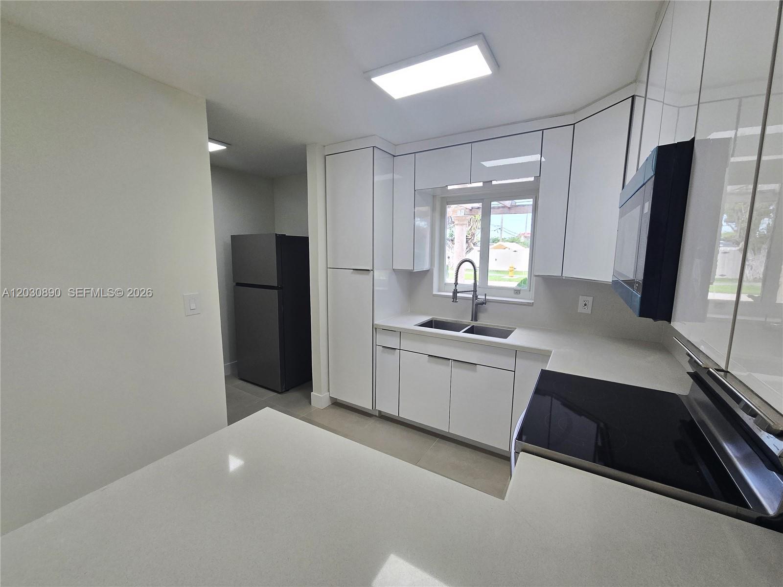 A modern kitchen features white cabinets, quartz countertops, a stainless steel sink, and black appliances — 8891 SW 36th St # 8891, Miami FL 33165, MIAMI, FL