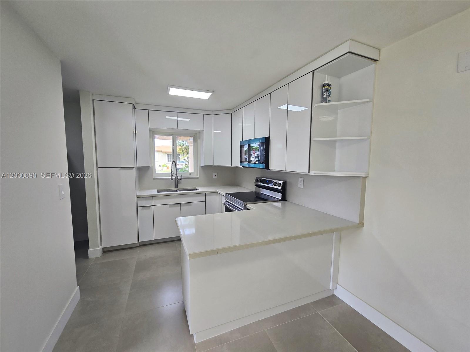 A modern kitchen features white glossy cabinets, a peninsula, and light-colored quartz countertops — 8891 SW 36th St # 8891, Miami FL 33165, MIAMI, FL