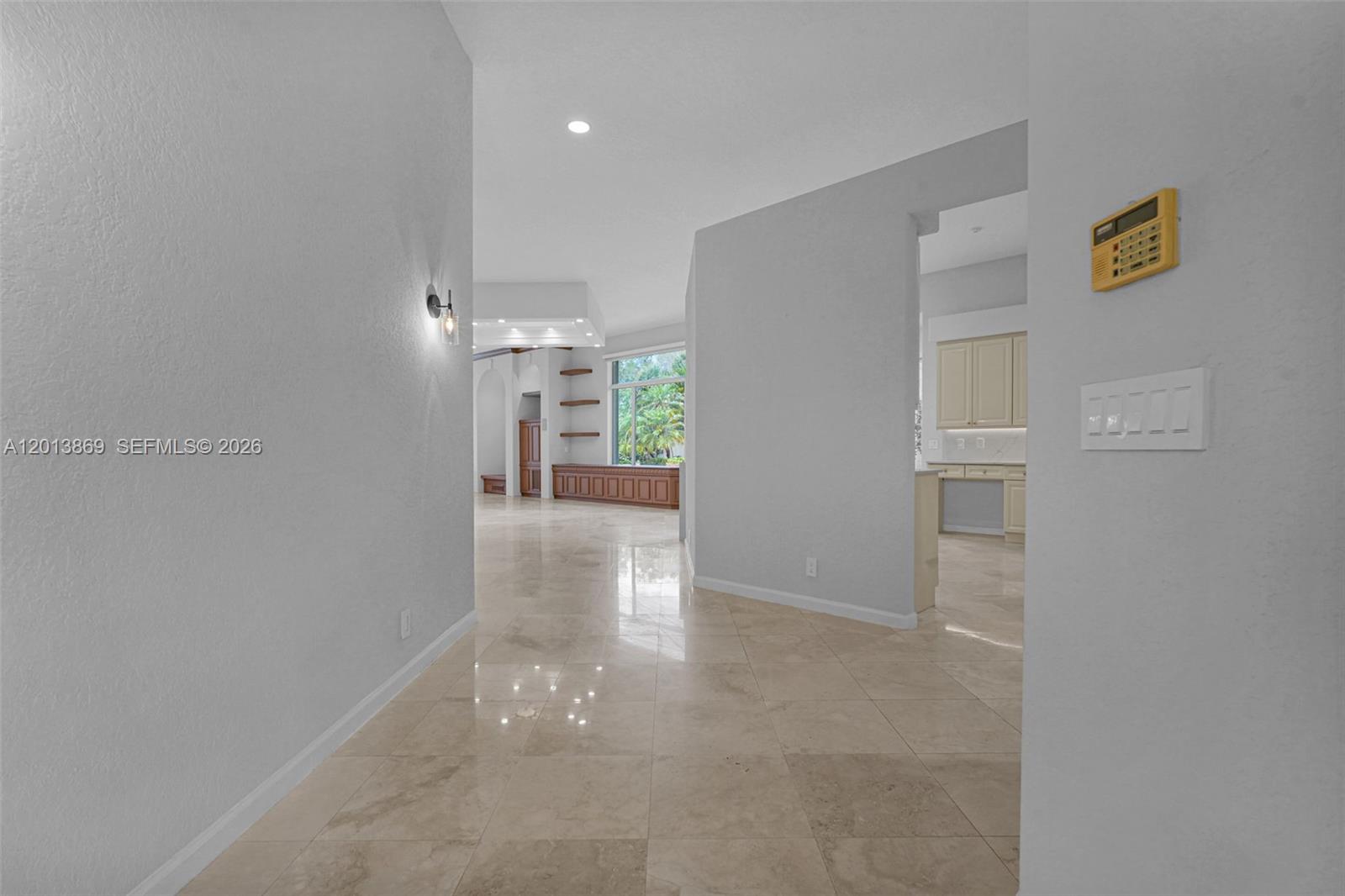 A tiled hallway leads into a bright living area with a large window and shelving — 2456 Bay Isle Court, Weston FL 33327, WESTON, FL