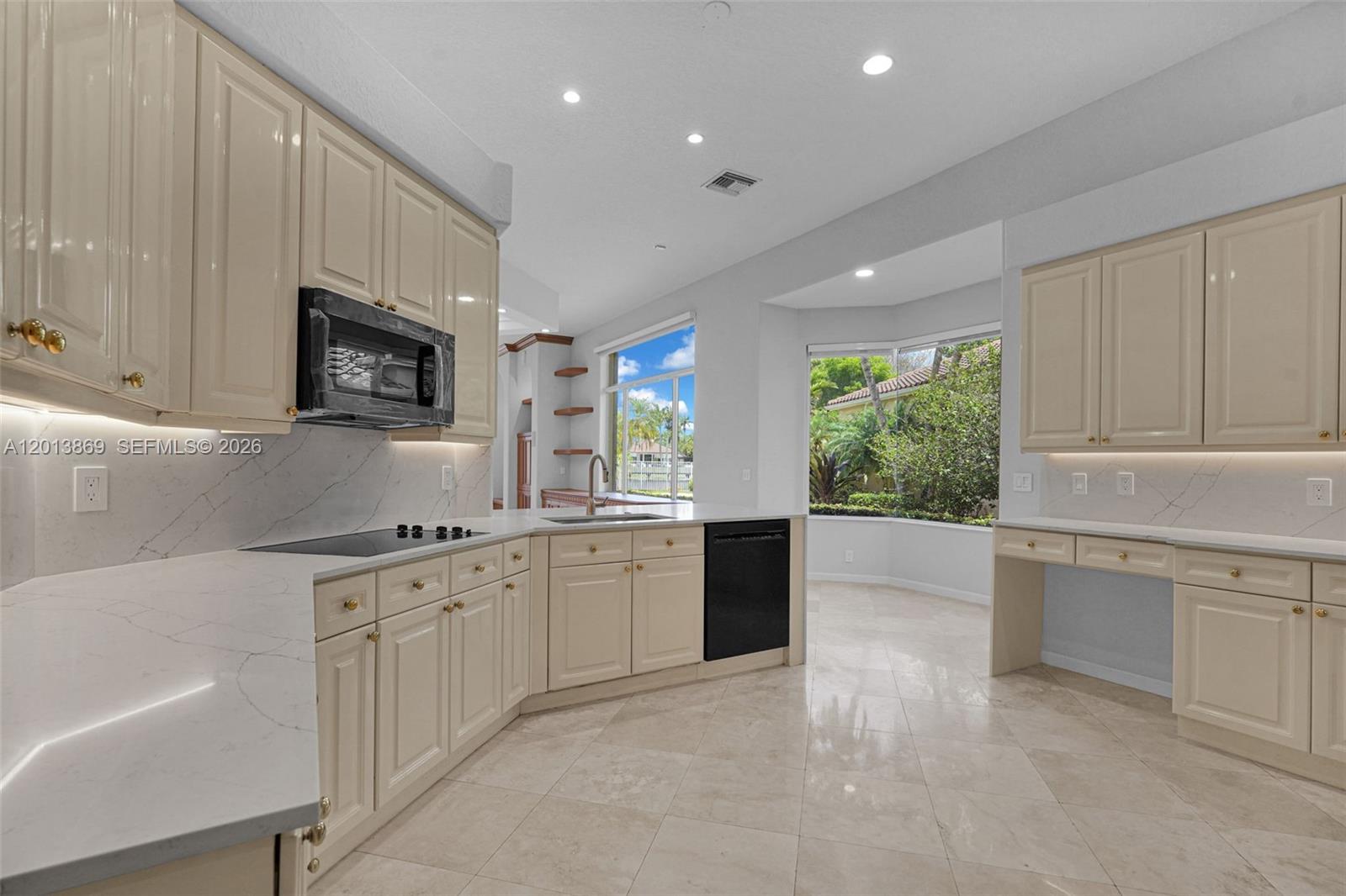 A kitchen features cream-colored cabinets, white marble-style countertops, a black dishwasher, and a bay window — 2456 Bay Isle Court, Weston FL 33327, WESTON, FL