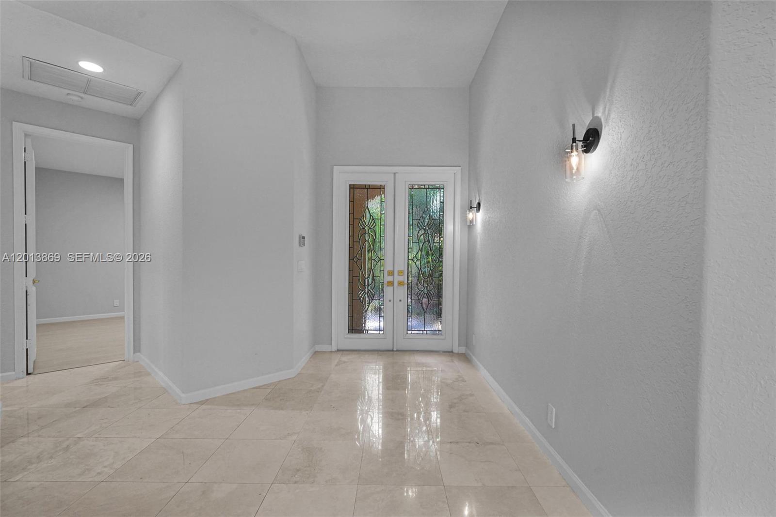 A bright foyer features light-colored tile flooring, white walls, and double glass-paneled entry doors — 2456 Bay Isle Court, Weston FL 33327, WESTON, FL