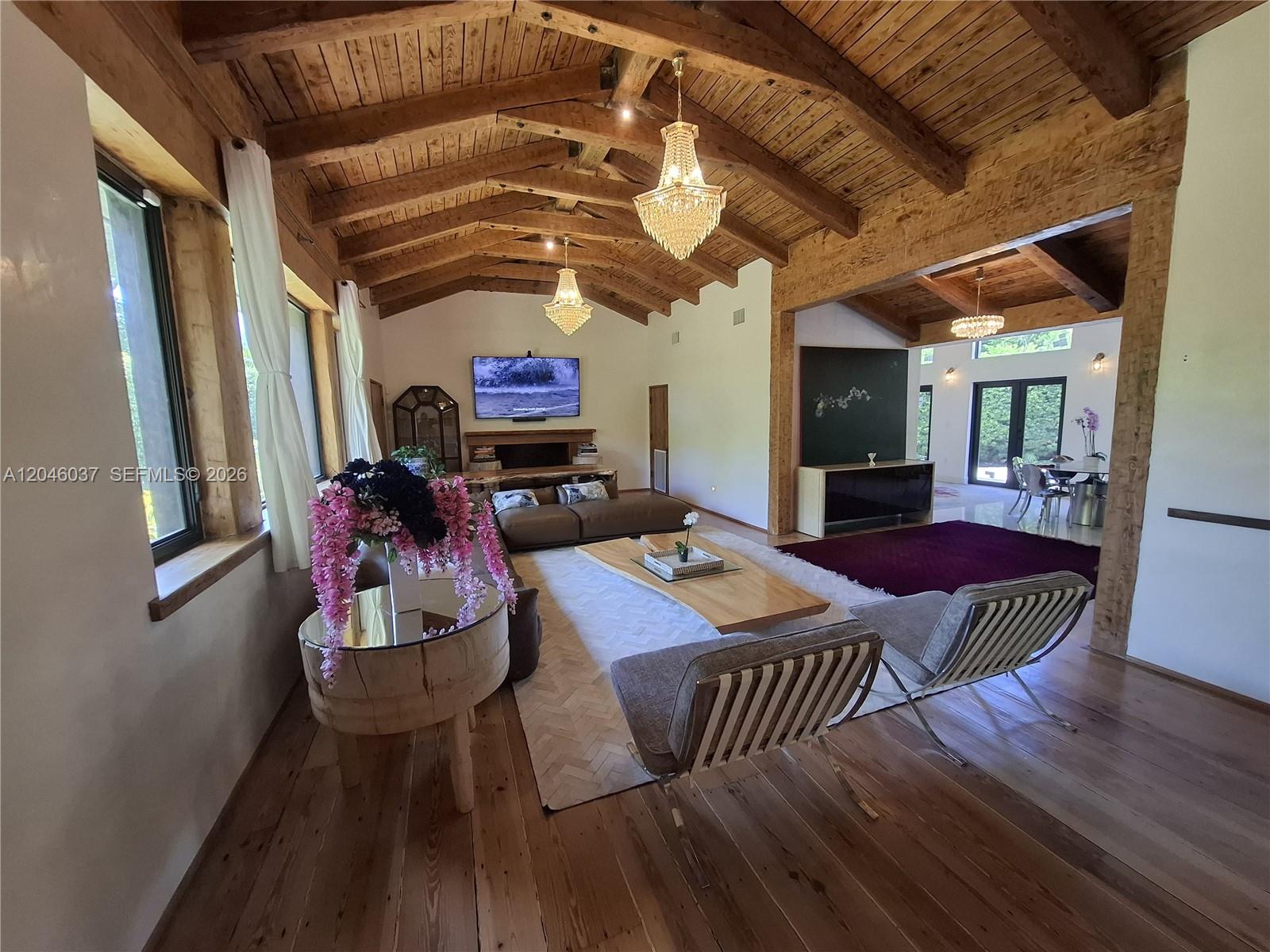 A living room features vaulted wood-beamed ceilings, crystal chandeliers, and hardwood floors — 6350 Pinetree Dr, Miami Beach FL 33141, MIAMI BEACH, FL