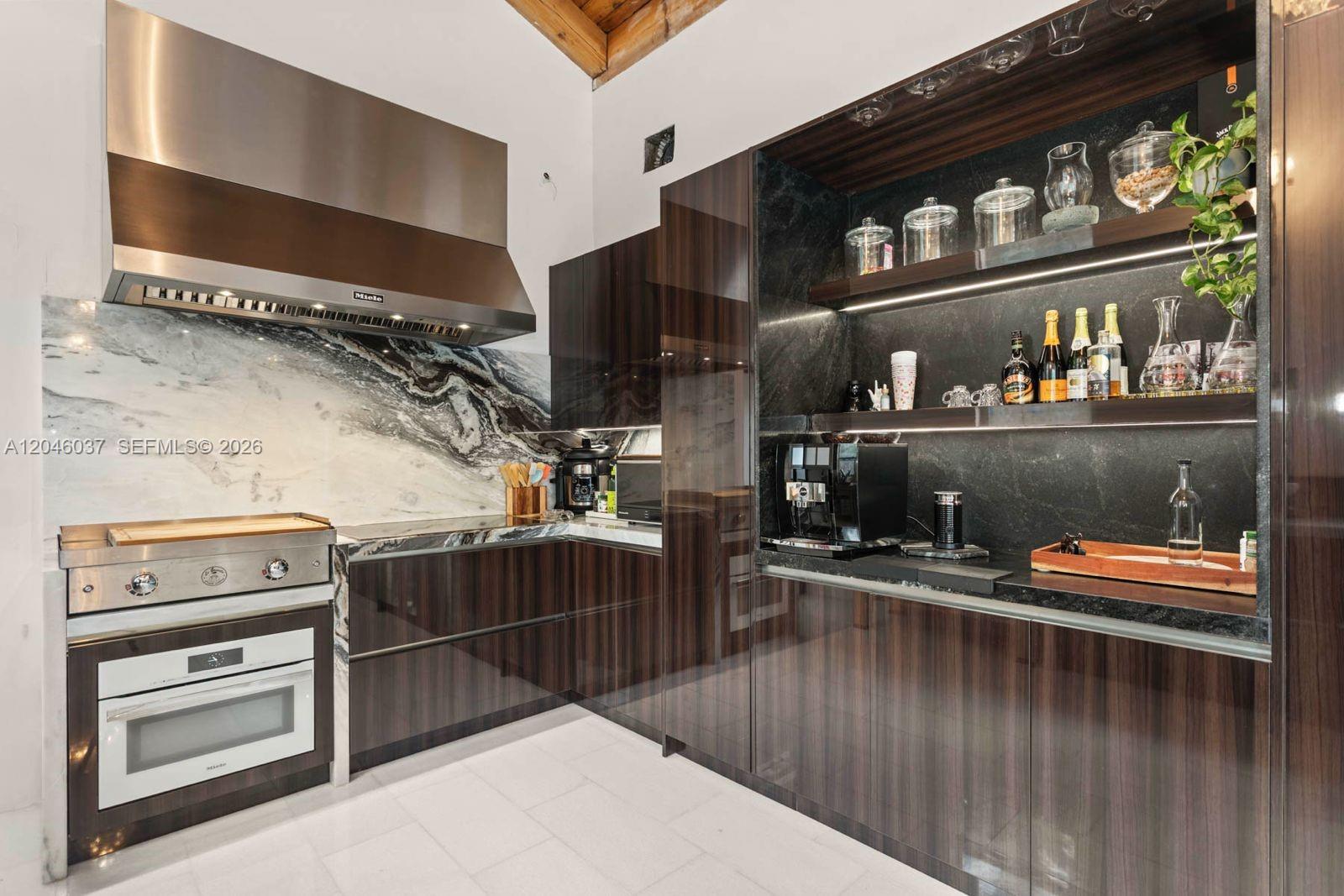A modern kitchen features dark wood cabinetry, a marble backsplash, and a stainless steel range — 6350 Pinetree Dr, Miami Beach FL 33141, MIAMI BEACH, FL