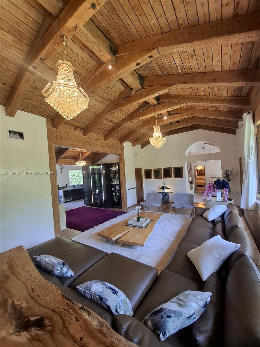 A living room features a vaulted wood-beam ceiling, two crystal chandeliers, and a leather sectional — 6350 Pinetree Dr, Miami Beach FL 33141, MIAMI BEACH, FL