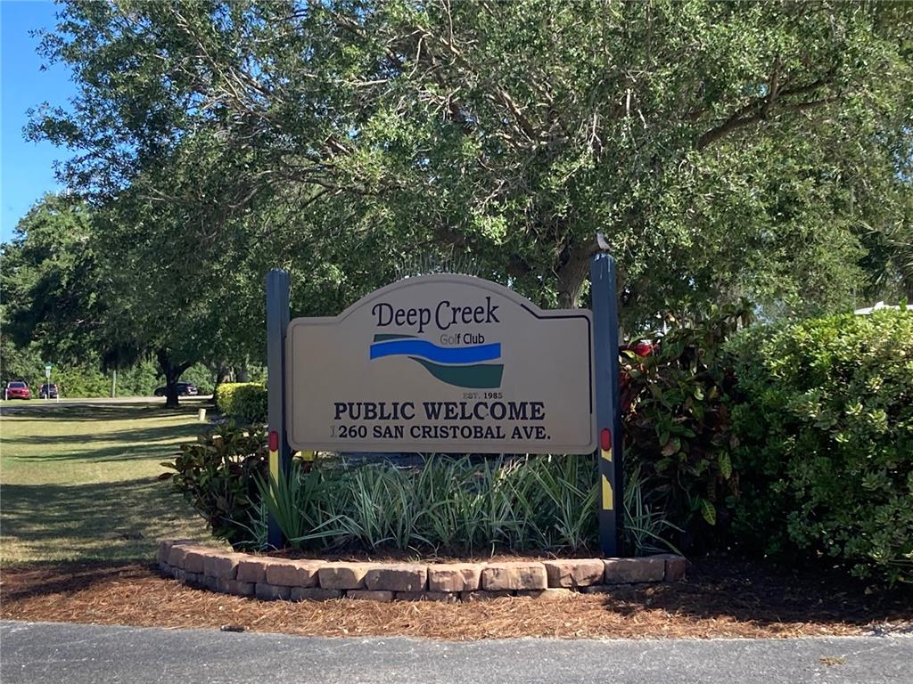 A sign for the Deep Creek Golf Club stands in a landscaped garden area — 25187 PALISADE ROAD, PUNTA GORDA, FL