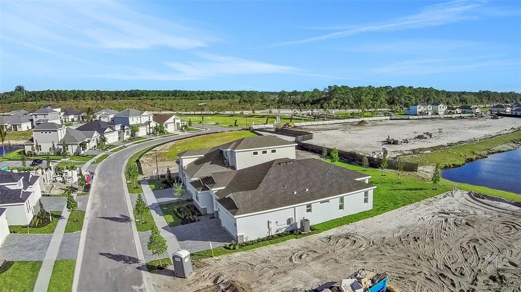 An aerial view shows a suburban house with a dark roof near a construction site — 10724 NW SUNCREST LOOP, PORT ST LUCIE, FL
