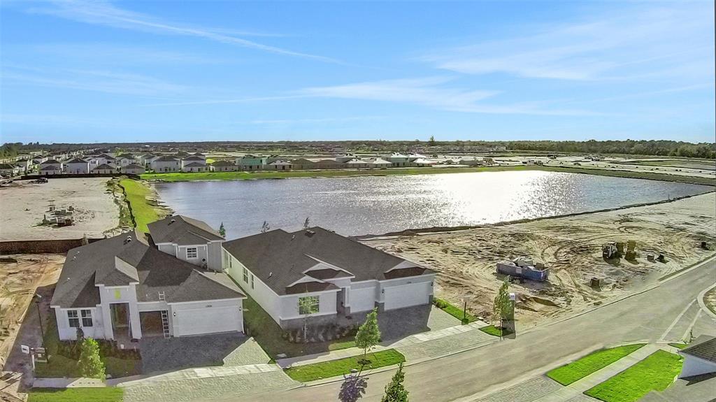 An aerial view shows two newly constructed houses next to a large retention pond — 10724 NW SUNCREST LOOP, PORT ST LUCIE, FL