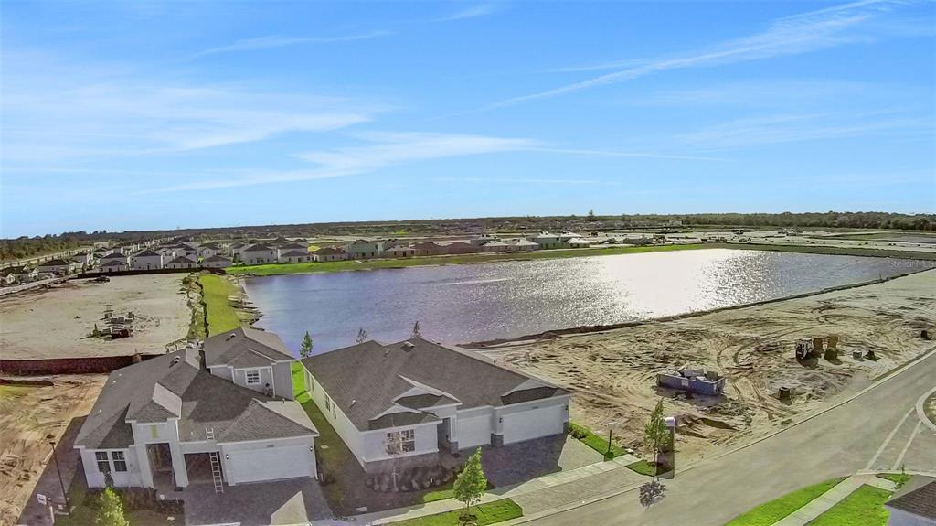 An aerial view shows two newly constructed houses next to a large retention pond — 10724 NW SUNCREST LOOP, PORT ST LUCIE, FL