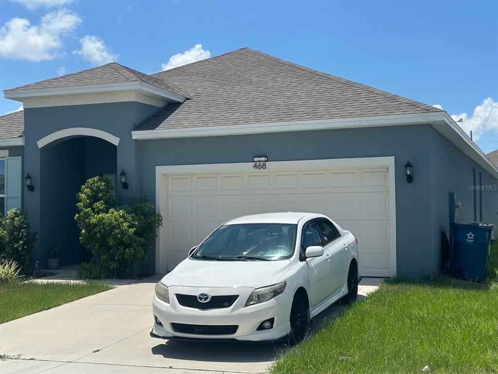 A white sedan is parked in the driveway of a gray single-story house — 468 SILVER PALM DRIVE, HAINES CITY, FL
