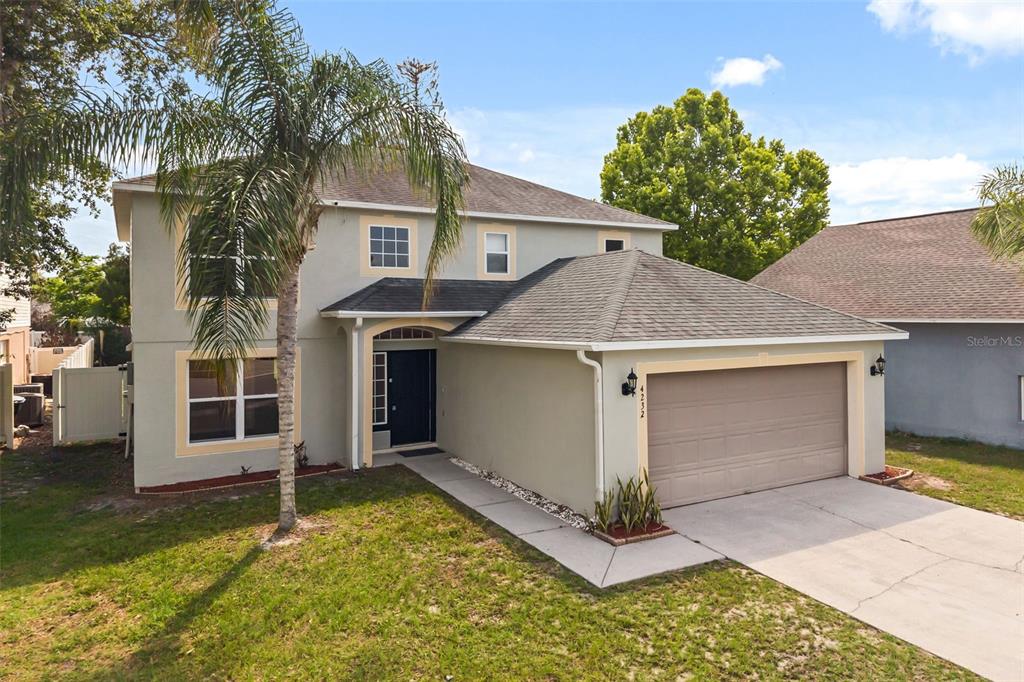 A two-story house with a beige stucco exterior, a two-car garage, and a palm tree — 4232 STONEFIELD DRIVE, ORLANDO, FL
