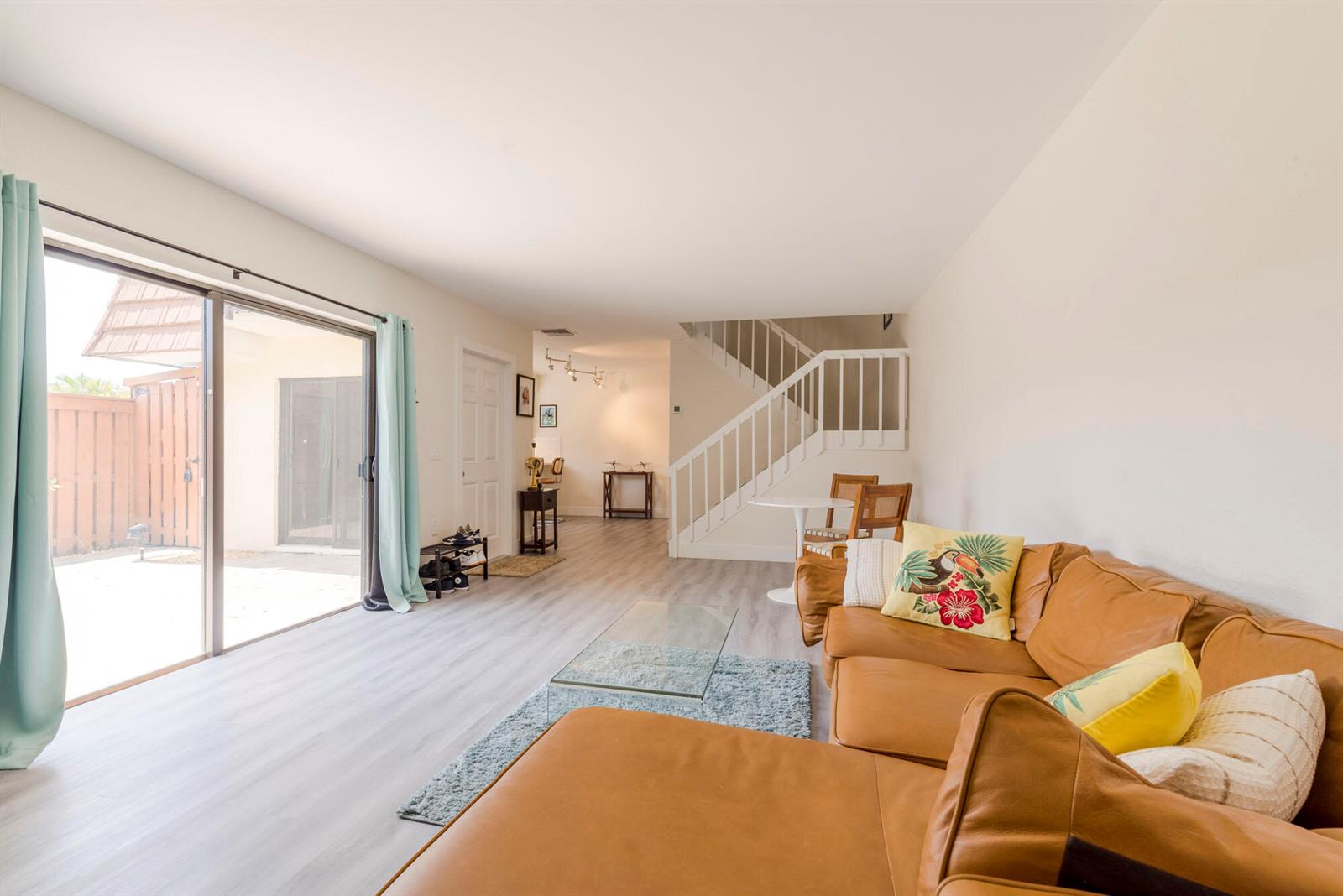 A living room features a tan leather sectional, glass coffee table, and stairs to the upper level — 3900 County Line Road # 21a, Tequesta FL 33469, TEQUESTA, FL
