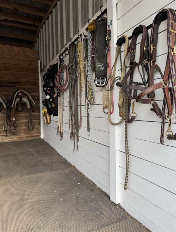 A tack room features white wooden walls lined with various horse bridles, halters, and saddles — 4260 NW 96TH LANE, OCALA, FL
