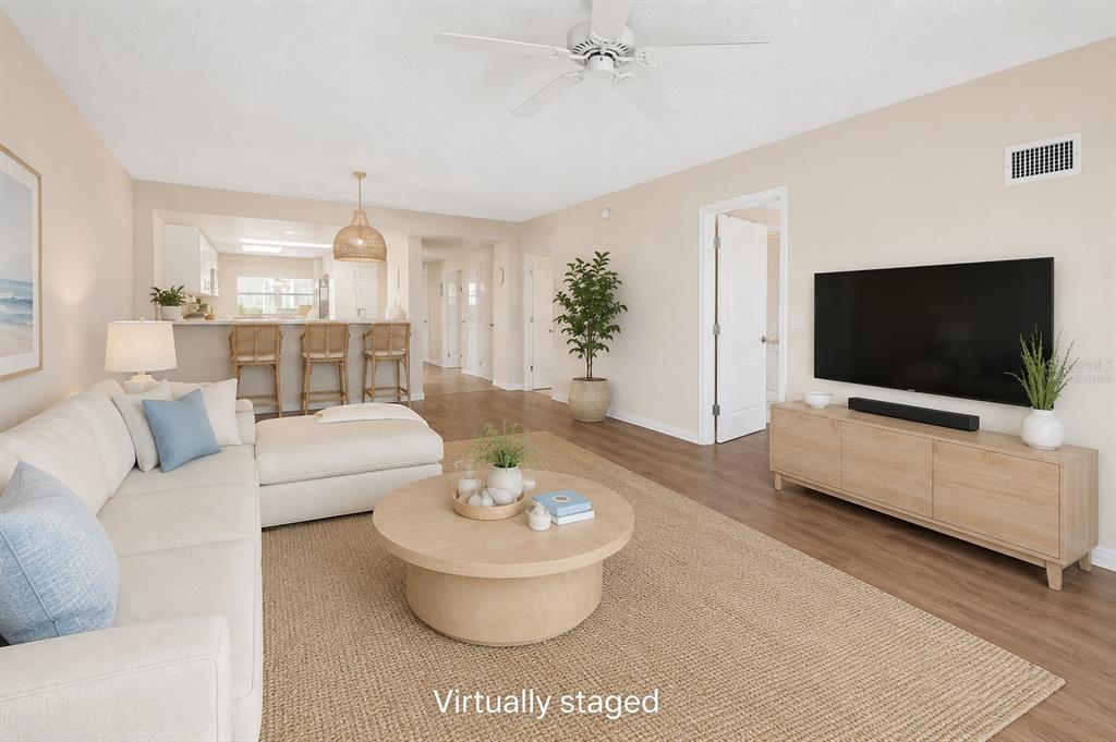 A virtually staged living room features a sectional sofa, round coffee table, and television console — 4 OCEANS WEST BLVD UNIT 606D, DAYTONA BEACH SHORES, FL