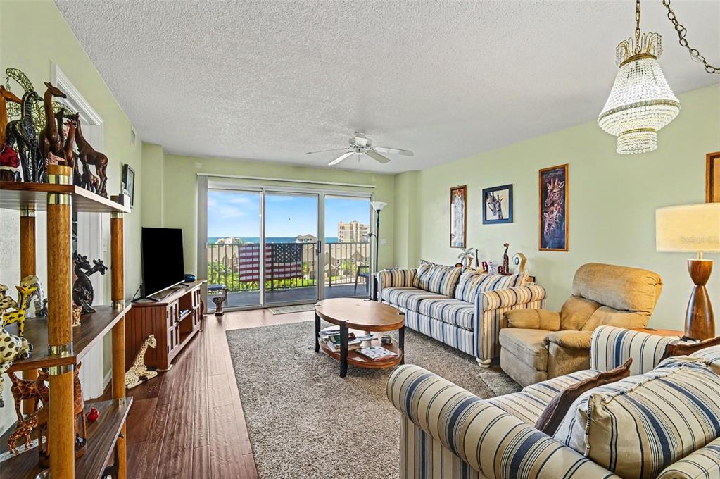 A living room with striped sofas, a wood coffee table, and a balcony overlooking the ocean — 4 OCEANS WEST BLVD UNIT 606D, DAYTONA BEACH SHORES, FL