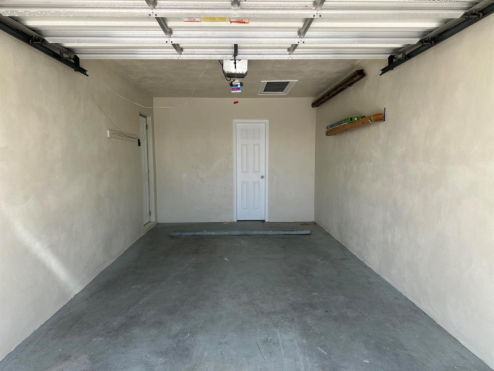 An empty garage with concrete floors, beige walls, a central door, and a ceiling opener — 728 Ridge Road # 31, Lantana FL 33462, LANTANA, FL