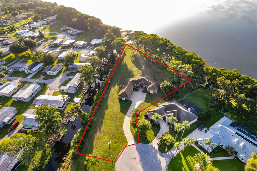 An aerial view shows a house on a large, waterfront lot with a paved driveway — 12131 EAGLES POINT COURT, GRAND ISLAND, FL