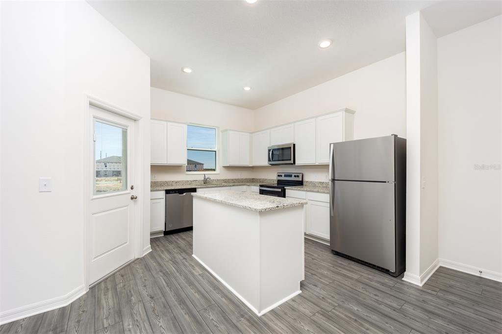 A kitchen features white cabinets, granite countertops, stainless steel appliances, and a central island — 672 POPPY LANE, DUNDEE, FL