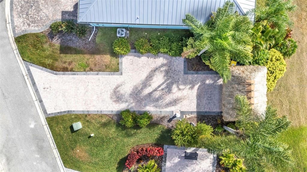 An aerial view shows a paved driveway, a thatched-roof structure, and landscaping beside a house — 3234 GREAT HERON LOOP, POLK CITY, FL