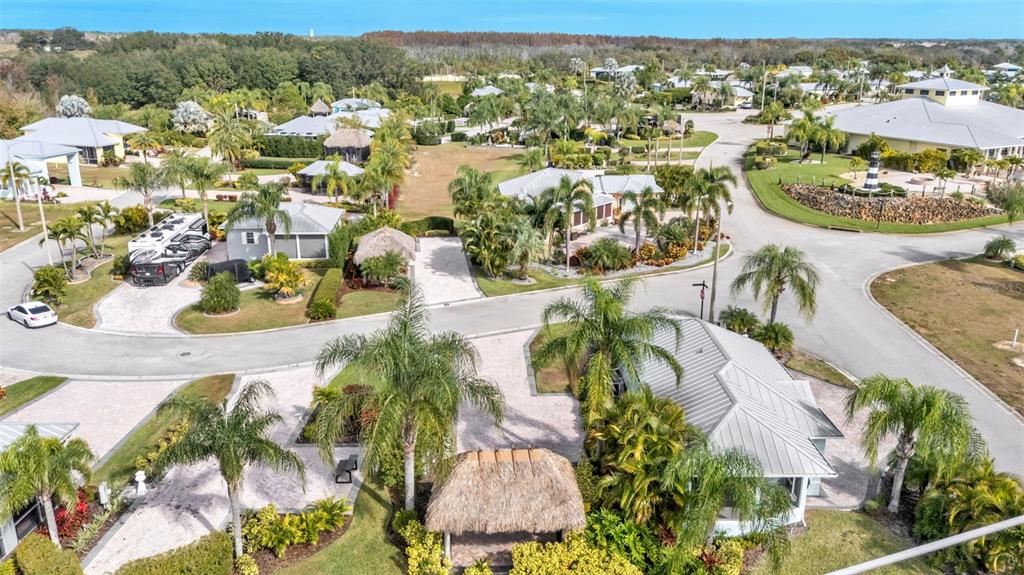 An aerial view of a residential community featuring houses, palm trees, and a tiki hut — 3234 GREAT HERON LOOP, POLK CITY, FL