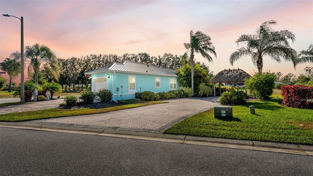 A light blue house with a metal roof and a tiki hut sits on a lot — 3234 GREAT HERON LOOP, POLK CITY, FL