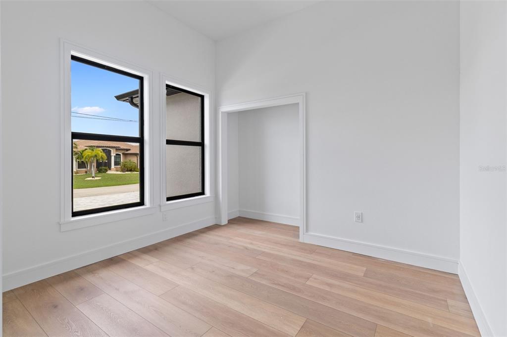 A bright room with light wood flooring, white walls, two windows, and a recessed alcove — 15381 ALSASK CIRCLE, PORT CHARLOTTE, FL