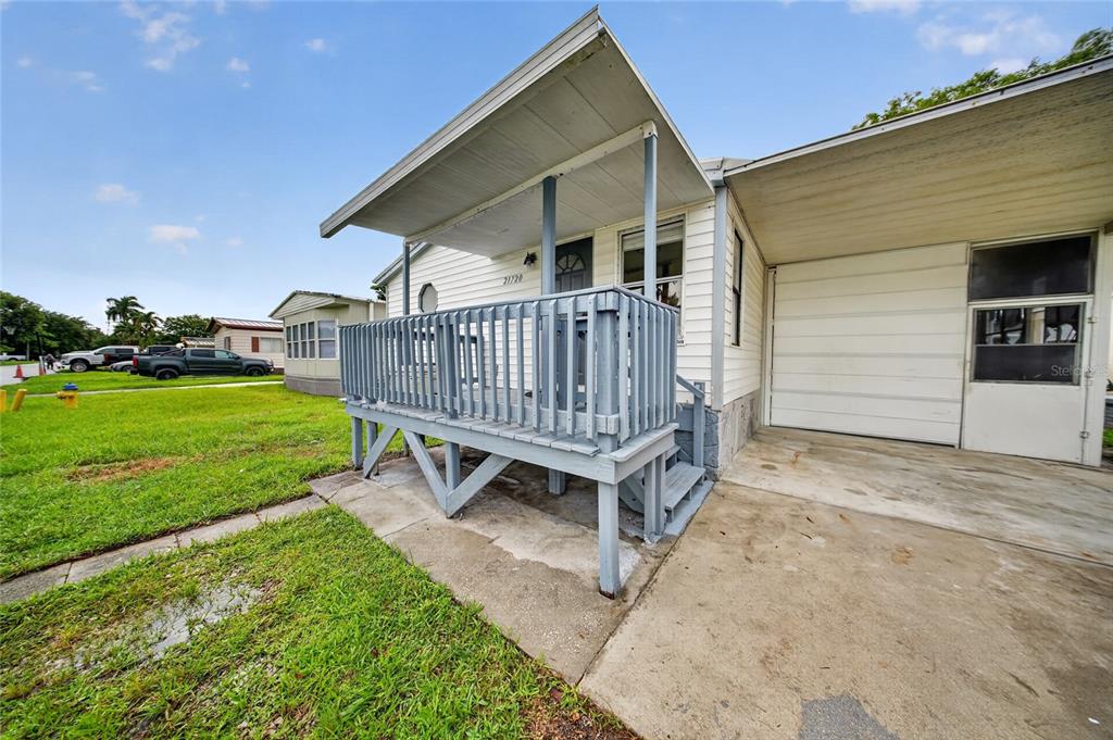 A mobile home exterior featuring a raised wooden porch, a concrete driveway, and a carport — 21720 NW 8TH COURT, PEMBROKE PINES, FL