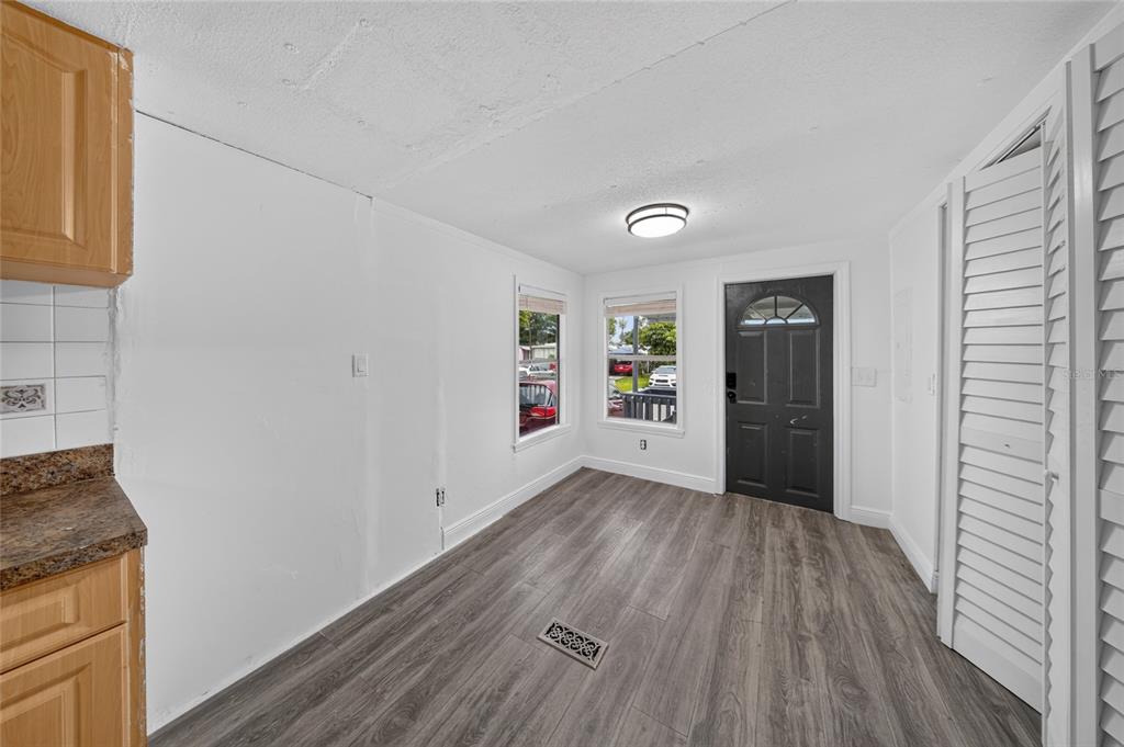 A kitchen dining area features wood-look flooring, white walls, a black door, and wood cabinets — 21720 NW 8TH COURT, PEMBROKE PINES, FL
