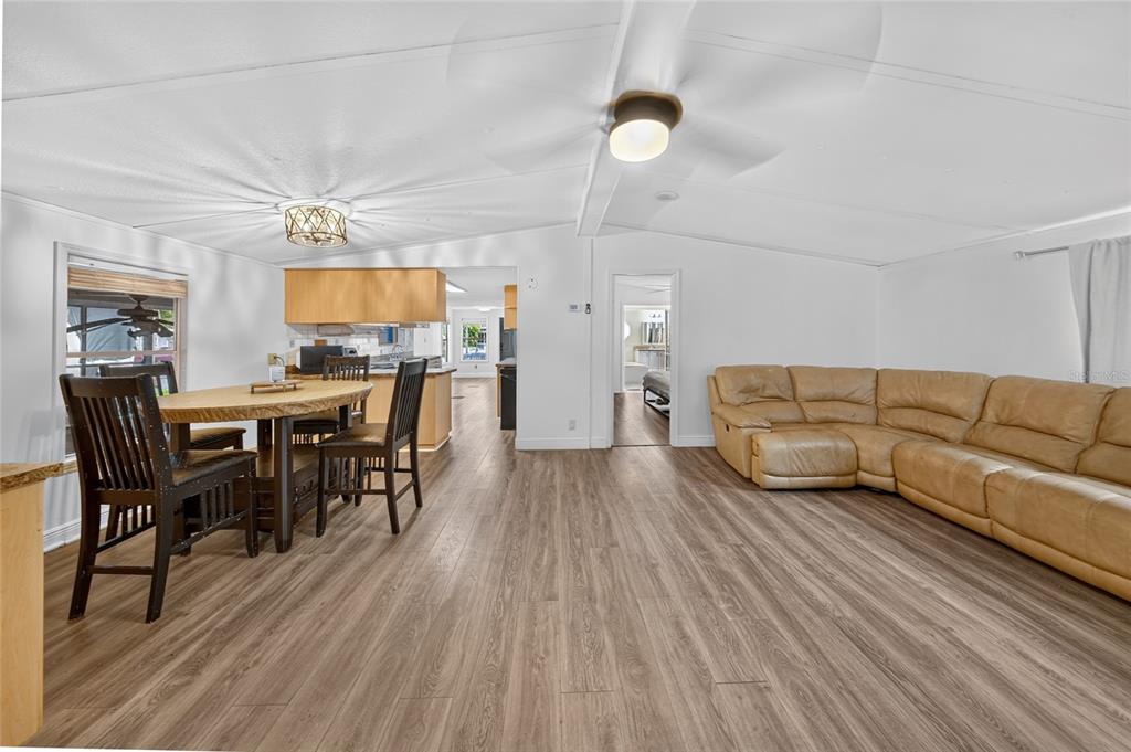 An open-concept living and dining area with wood-look flooring, a tan sectional, and light walls — 21720 NW 8TH COURT, PEMBROKE PINES, FL