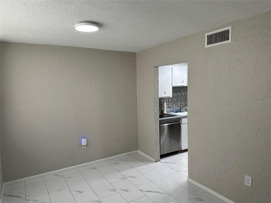 A dining area with white marble-look tile flooring and a doorway leading to a kitchen — 2623 SEVILLE BOULEVARD UNIT 202, CLEARWATER, FL