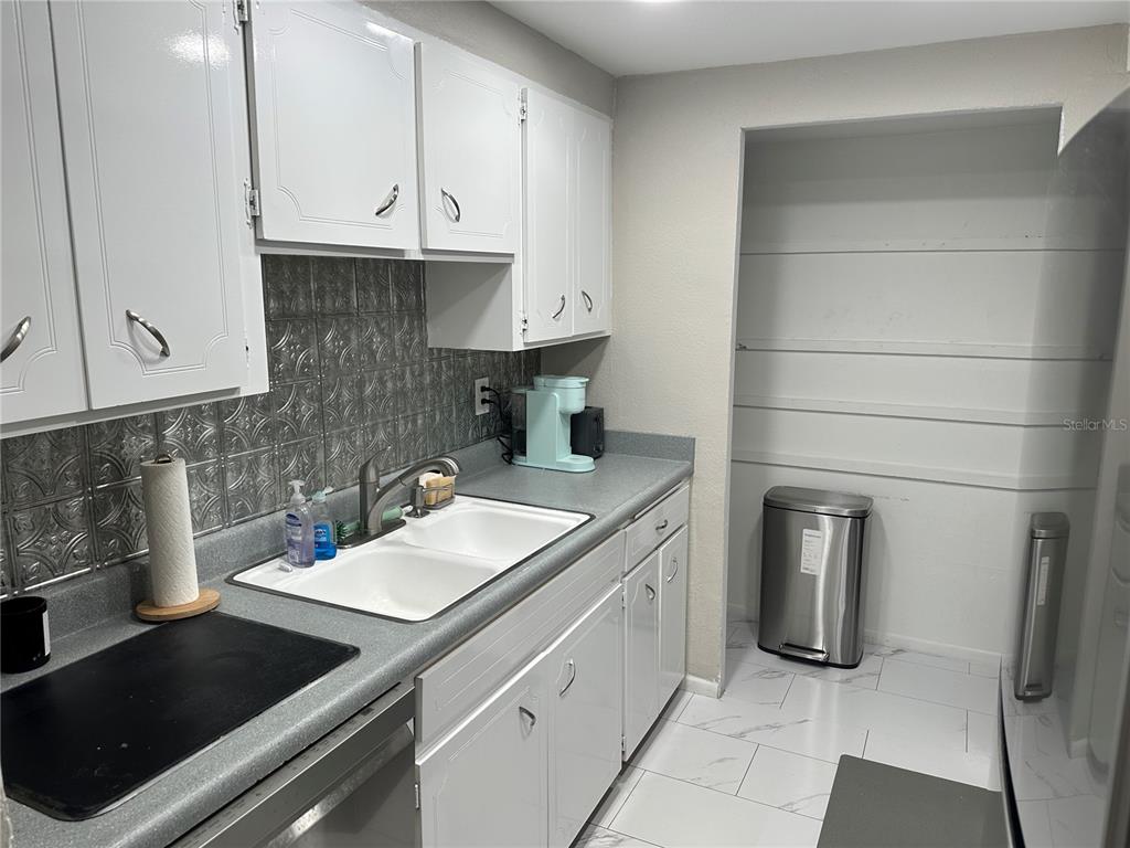 A kitchen features white cabinets, a gray countertop, a tiled backsplash, and a white sink — 2623 SEVILLE BOULEVARD UNIT 202, CLEARWATER, FL
