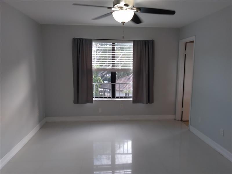 An empty room with light gray walls, white tile flooring, a ceiling fan, and window curtains — 4261 W Mcnab Road # 32, Pompano Beach FL 33069, POMPANO BEACH, FL