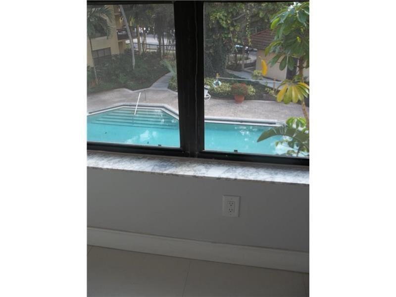 A view of a swimming pool through a window with a marble sill and outlet — 4261 W Mcnab Road # 32, Pompano Beach FL 33069, POMPANO BEACH, FL