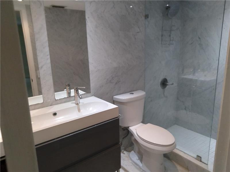 A bathroom features a vanity with a white sink, a toilet, and a glass-enclosed shower — 4261 W Mcnab Road # 32, Pompano Beach FL 33069, POMPANO BEACH, FL