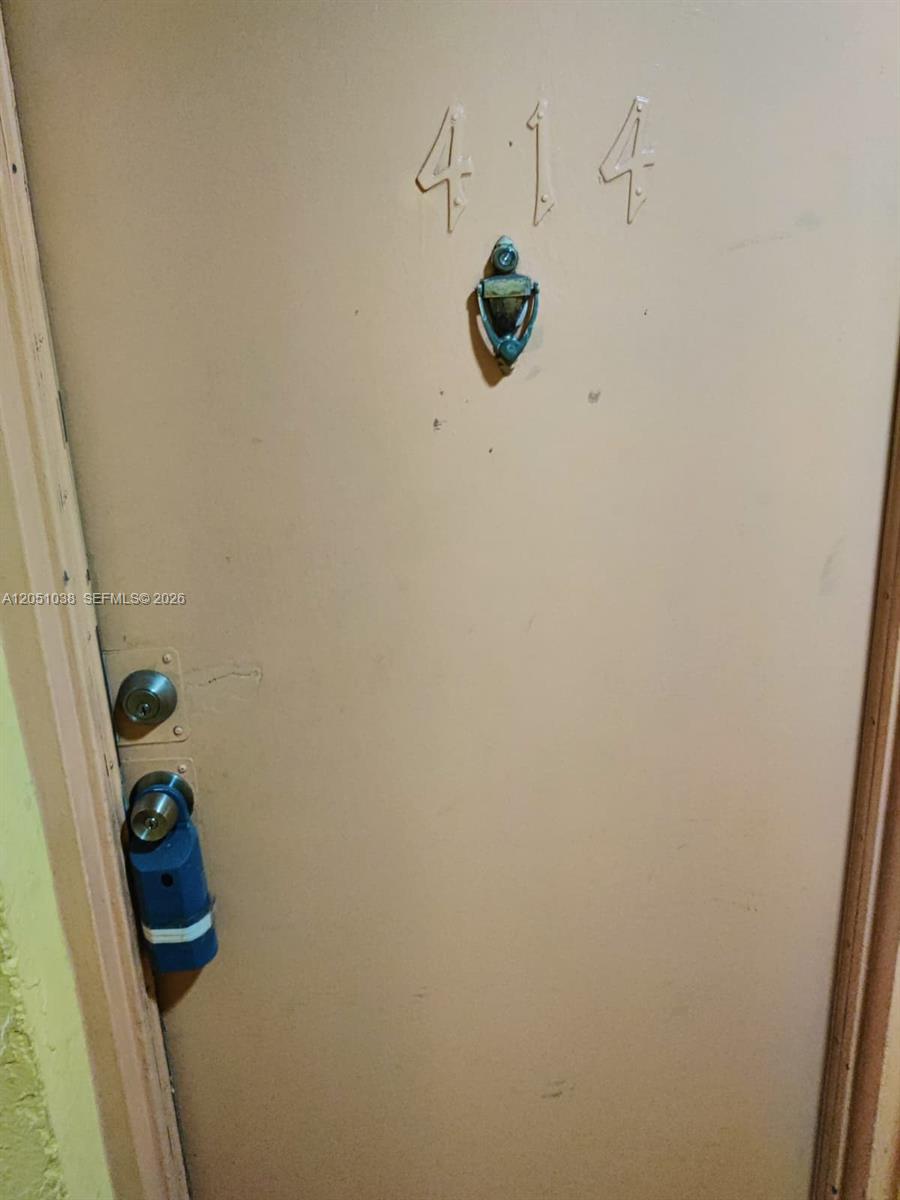 A beige apartment door features the number 414, a metal door knocker, and a blue lockbox — 666 W 81st St # 414, Hialeah FL 33014, HIALEAH, FL