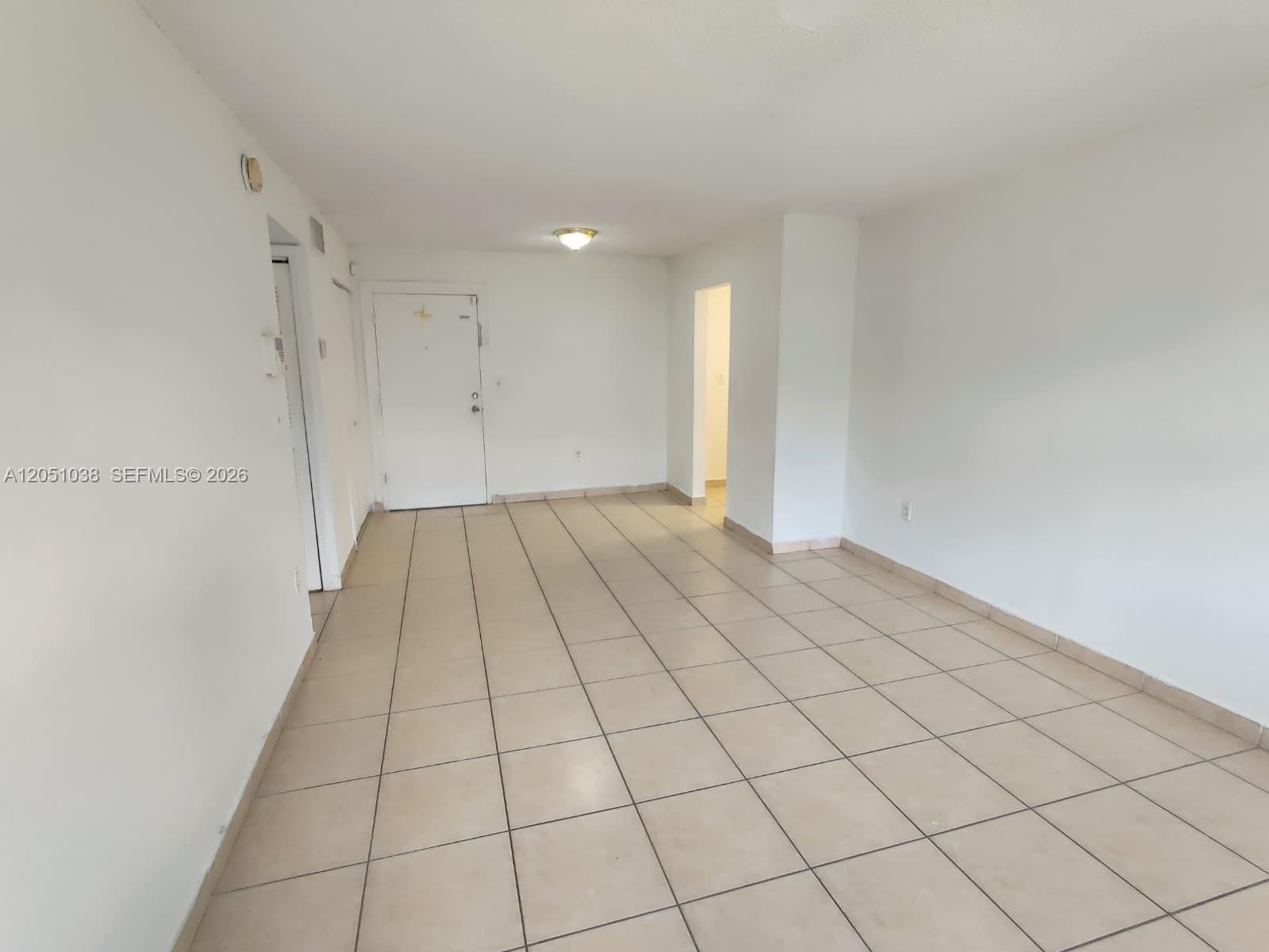 A sparsely furnished room features white walls, beige tile flooring, and a central ceiling light — 666 W 81st St # 414, Hialeah FL 33014, HIALEAH, FL
