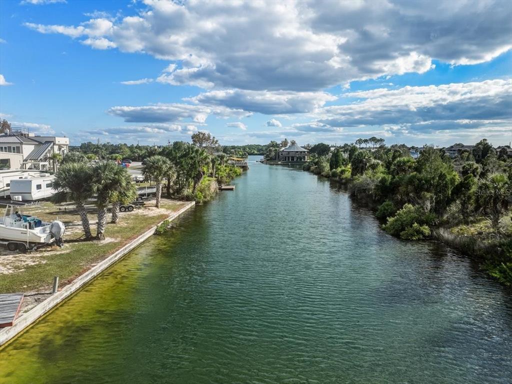 An aerial view shows a canal lined with palm trees, vegetation, and waterfront properties — 4001 SHOAL LINE BOULEVARD, HERNANDO BEACH, FL
