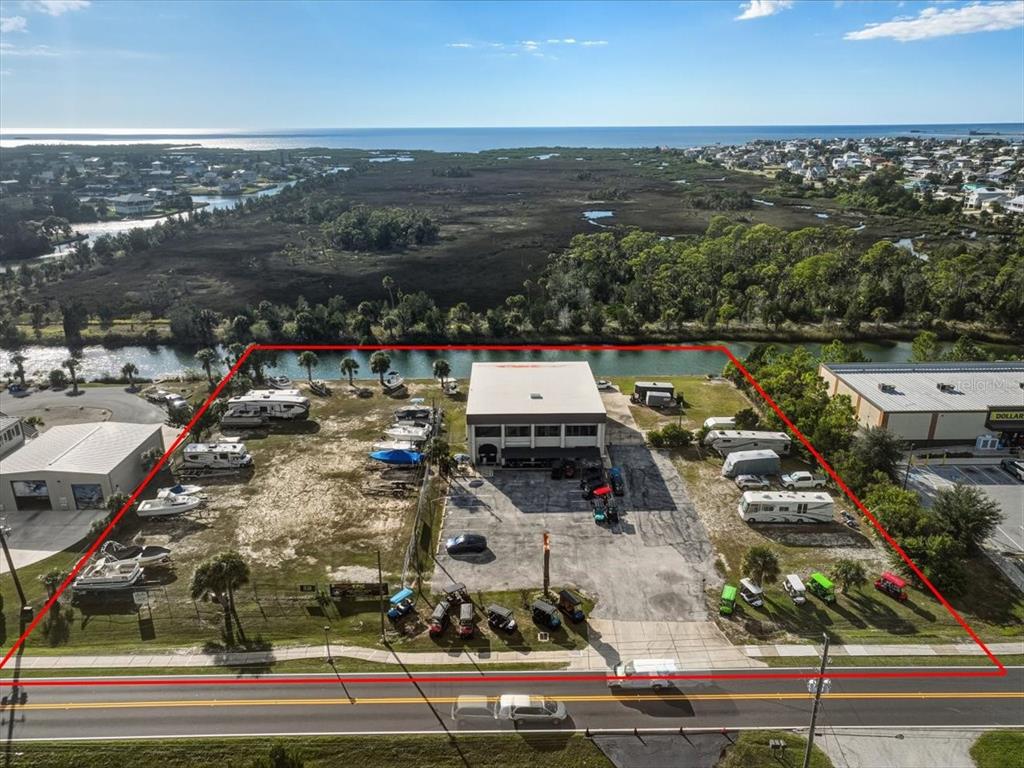 An aerial view shows a commercial building and storage lot bordered by a canal — 4001 SHOAL LINE BOULEVARD, HERNANDO BEACH, FL