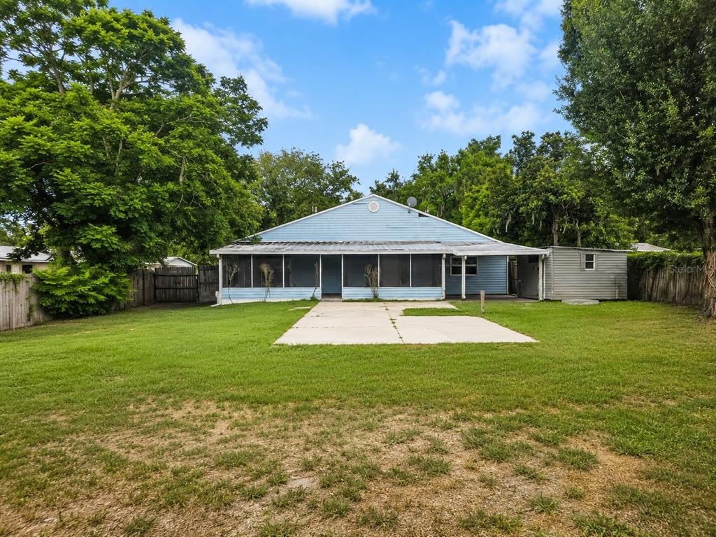 The exterior of a light blue house features a large screened-in porch and concrete patio — 521 GREEN CIR, FORT MEADE, FL