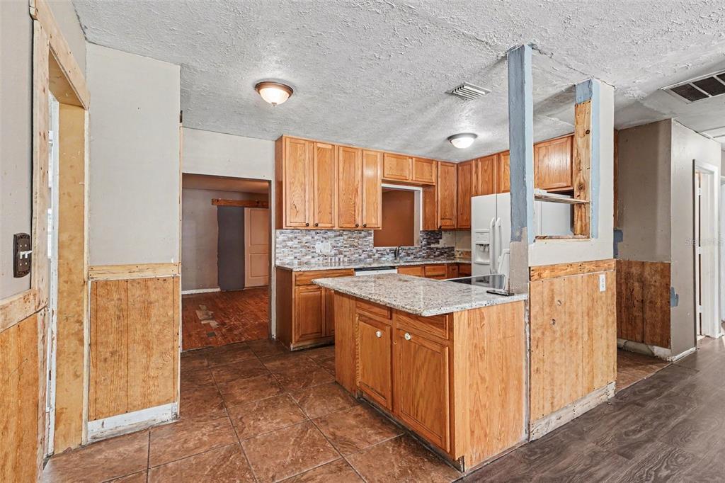 A kitchen with wood cabinets, granite countertops, and unfinished wall paneling in a home interior — 521 GREEN CIR, FORT MEADE, FL