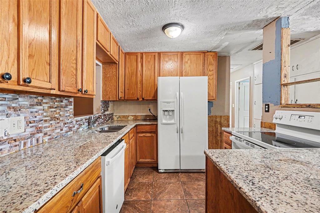 A kitchen with oak cabinets, granite countertops, a white refrigerator, and a tiled floor — 521 GREEN CIR, FORT MEADE, FL